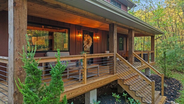 Una terraza de madera con mobiliario exterior y una escalera que conduce a un espacio cubierto.