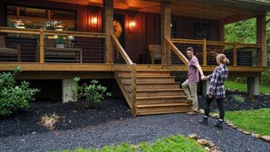 Una escalera de madera que lleva a una terraza techada con mobiliario exterior.
