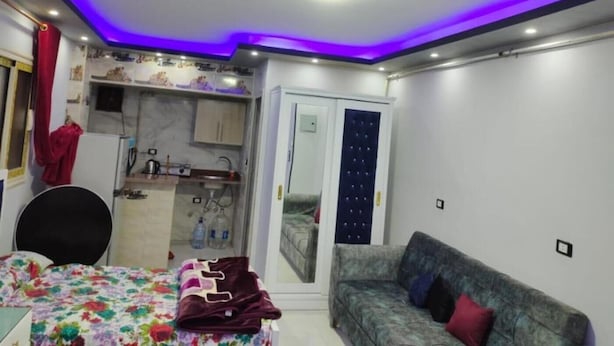 Een slaapkamer met een bed, een bank, een kleine kitchenette en een badkamer.