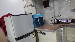 Een keuken met een koelkast, een blauwe doos, een fornuis en een betegelde achterwand.