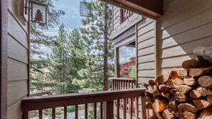 A balcony with a view of trees and a stack of firewood. - Pet-Friendly, Updated Décor. Washer/Dryer, Balcony, Short Walk to The Village (Mammoth Lakes)