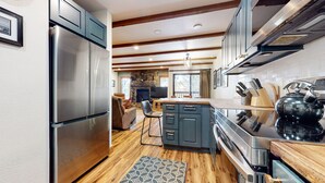 A modern kitchen with stainless steel appliances, dark cabinetry, and a wooden floor. - Pet-Friendly, Updated Décor. Washer/Dryer, Balcony, Short Walk to The Village (Mammoth Lakes)