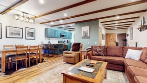 A cozy living room with a wooden coffee table, a brown sofa, and a dining area with wooden chairs and a table. - Pet-Friendly, Updated Décor. Washer/Dryer, Balcony, Short Walk to The Village (Mammoth Lakes)