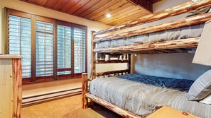 Uma cama de beliche com vista para uma floresta pela janela.