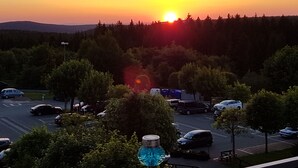 Ein Parkplatz mit Autos und Bäumen im Abendlicht.