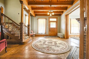 Staircase leads to an upper level, with a large rug and wooden door.