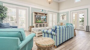 A spacious living room with a large television, comfortable seating, and a decorative ceiling light.