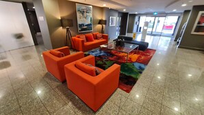 A lobby with orange seating, a glass coffee table, and a colorful rug. - 1BR Executive Apartment, in City Centre (Braddon)