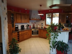 Una cocina con armarios de madera, una estufa y un lavaplatos. Hay plantas y electrodomésticos en las encimeras.