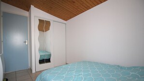 Un dormitorio con cama, una puerta y un ventanal pequeño.