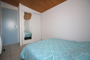 A bedroom with a bed, a door, and a small window.