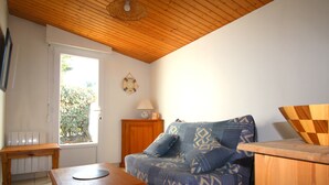 Un salón acogedor con techo de madera, un sofá estampado, una mesita de madera y una ventana con vistas a zonas verdes.