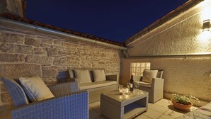 An outdoor seating area with wicker furniture, a stone wall, and a potted plant. - Nice family house for 2 to 4 people (Ližnjan)