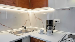 A modern kitchen with a white countertop, a stainless steel sink, a coffee maker, and wooden cabinets. - Nice family house for 2 to 4 people (Ližnjan)