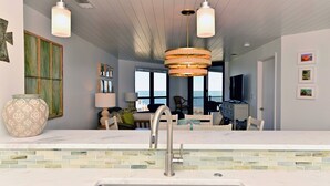Una cocina moderna con un lavaplatos integrado, una zona de comedor con vistas y un florero grande sobre la encimera.