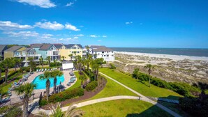 Un hotel frente a la playa con piscina, varias habitaciones e vista al mar.