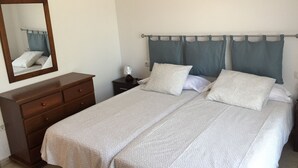 A bedroom with a bed, a dresser, a nightstand, a lamp, and a mirror. - LA LAJITA OCEAN VIEW 2 (La Lajita)
