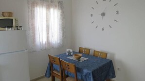 A dining area with a table covered by a blue tablecloth, wooden chairs, and a wall clock. - LA LAJITA OCEAN VIEW 2 (La Lajita)