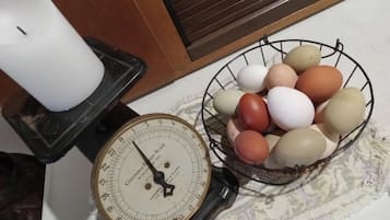 Une cuisine avec une bougie blanche posée sur un chandelier, une balance et un panier en fil métallique contenant des œufs.
