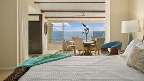 A hotel room with a bed, a dining area, and a view of the ocean. - Hawaii Life Rentals Presents Puu Poa 307 (Princeville)