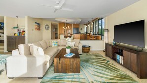 A modern living room with a sofa, coffee table, and TV stand. - Hawaii Life Rentals Presents Puu Poa 307 (Princeville)