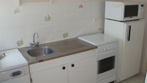 A compact kitchen with white cabinets, a stainless steel sink, a microwave, and a built-in oven. - apartment in pretty village (Lumio)