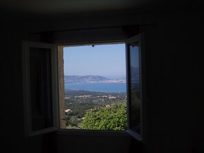 A room with a window overlooking a coastal landscape.