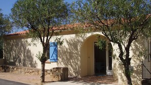 A building with a tiled roof, an arched doorway, and a small tree in front. - apartment in pretty village (Lumio)