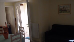 A room with a dining table, chairs, a black sofa, and a radiator. - apartment in pretty village (Lumio)