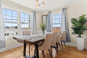 A dining area with a wooden table, six chairs, and a potted plant.