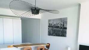 A modern living room with a blue armchair, a yellow armchair, and a wooden coffee table. There is a kitchen area with a bar counter and stools. A black and white photograph is displayed on the wall. - Superb apartment with sea and mountain views (Canet-en-Roussillon)