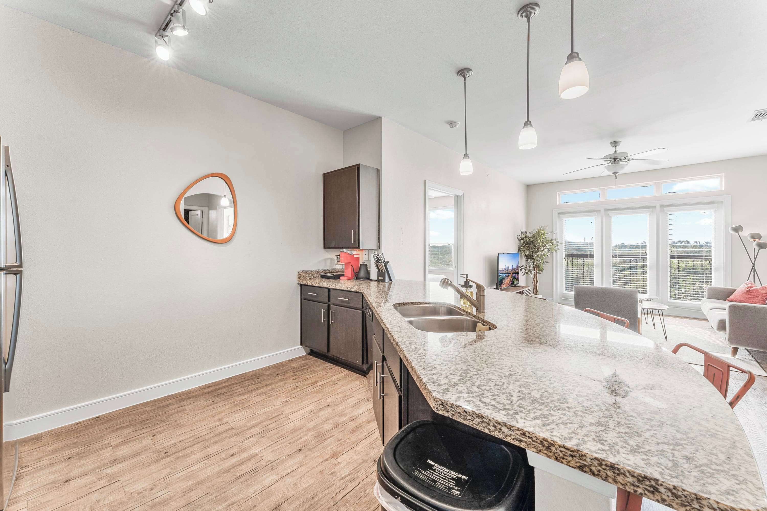 A modern kitchen with granite countertops, a built-in oven, and a large window.