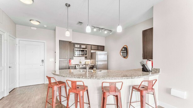 A modern kitchen with a central island, stainless steel appliances, and red bar stools. - Airy SoCo 2BR King Suite w/ GymPickleballLaundry (Austin)