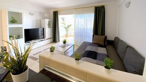 A modern living room with a sofa, TV, and a dining area. - Ocean Golf & Country Club A2 (Oasis del Sur)