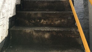 A set of stone steps with a yellow handrail leading up to a white gate. - Homely 2- bed Apartment -ground Floor-sleeps 4 (Ilfracombe)