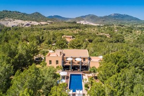 Uma villa com piscina, rodeada por árvores densas e montanhas ao fundo.