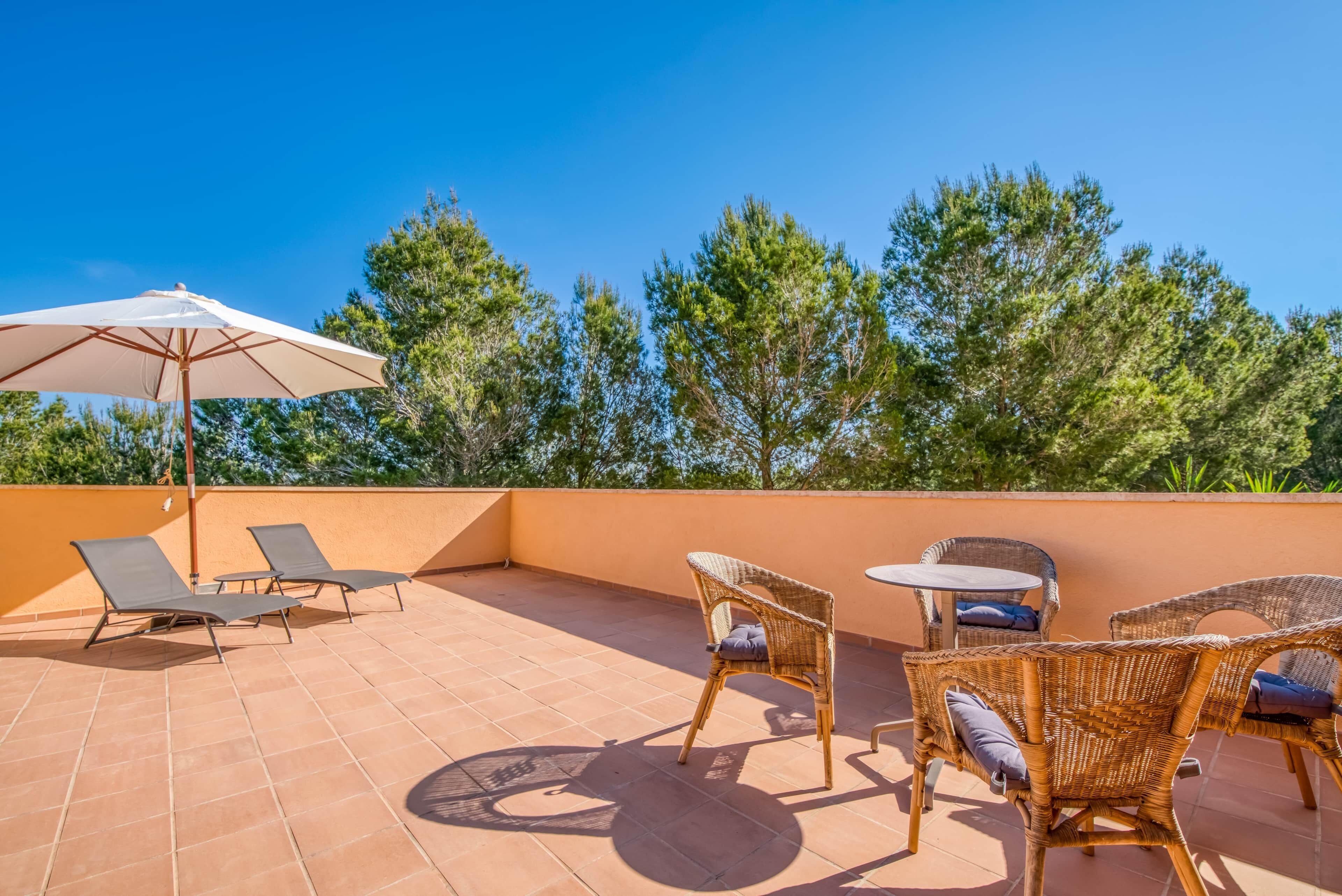 A terrace with wicker furniture, a table, and an umbrella.