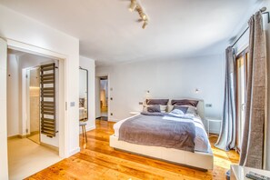 Quarto com cama, piso de madeira, closet espaçoso e vista pela janela.