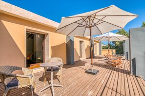 A wooden deck with outdoor furniture, including chairs and a table, and umbrellas.