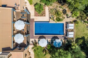An aerial view of a hotel with a swimming pool, outdoor seating, and lush landscaping.