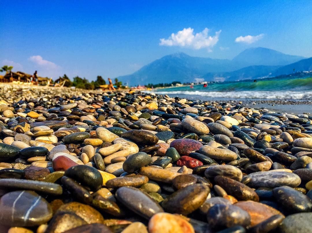 Une plage de galets avec une montagne en arrière-plan.