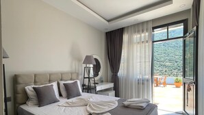 Ein modernes Hotelzimmer mit einem großen Bett, einem Schreibtisch und Blick auf einen Balkon mit Gartenmöbeln.