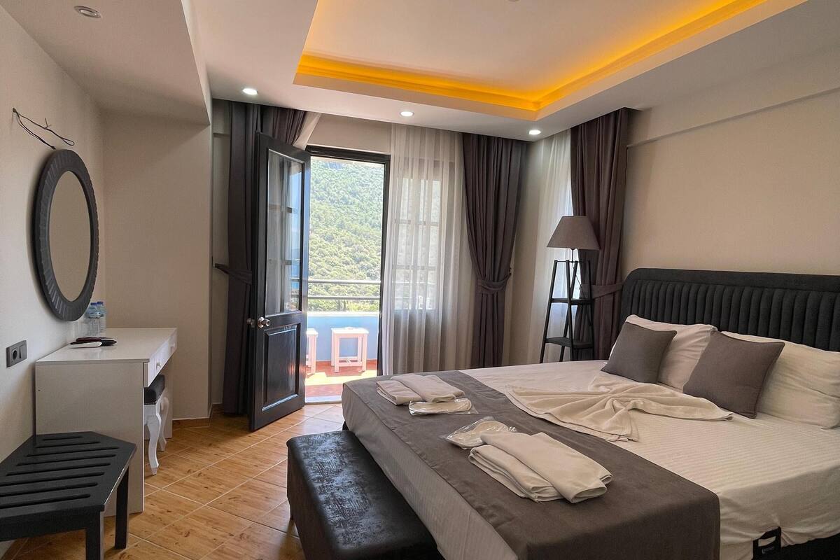 Een moderne slaapkamer met een groot bed, nachtkastjes, een bureau en uitzicht op de omgeving.