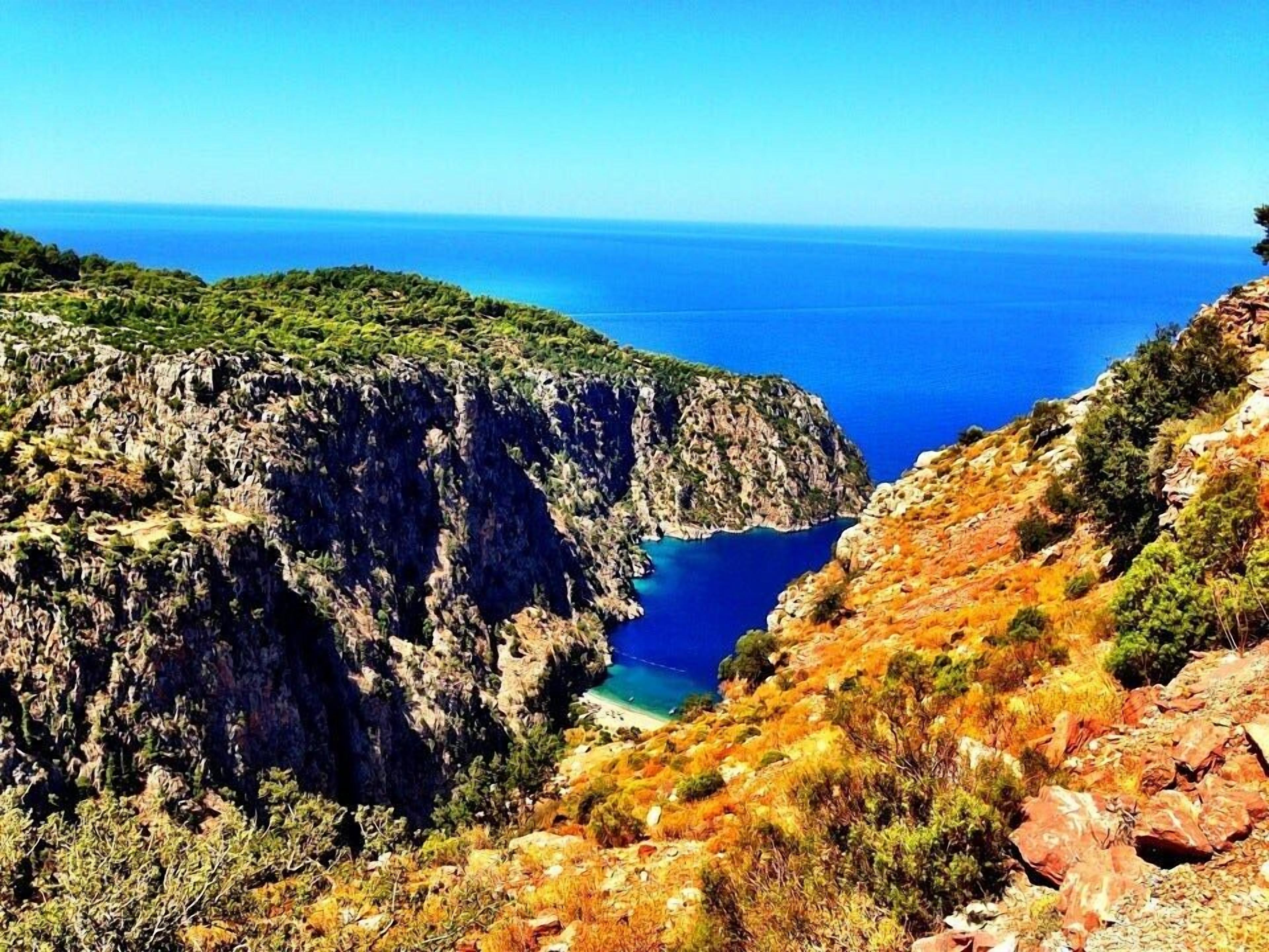 A rugged cliffside with a clear view of the sea.