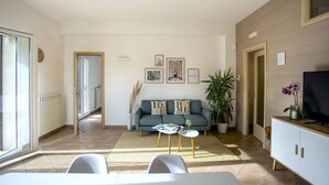 A modern living room with a sofa, coffee table, and TV stand. There is a plant and artwork on the walls. - Isula Relax - Villa with pool (Modica)