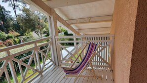 Une véranda couverte avec une balustrade en bois et un hamac à rayures.