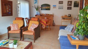 Un salon avec des meubles en osier, un canapé bleu et une table à manger.