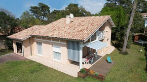 Une maison à deux étages, avec un toit en tuiles, un balcon et une terrasse couverte.