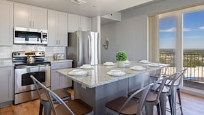 A modern kitchen with granite countertops, stainless steel appliances, and a large island with bar stools. - Luxury and Spacious Condo With Spectacular View (Panama City Beach)