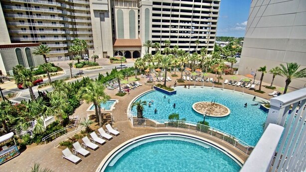 A hotel pool area with multiple pools, palm trees, and lounge chairs. - Luxury and Spacious Condo With Spectacular View (Panama City Beach)